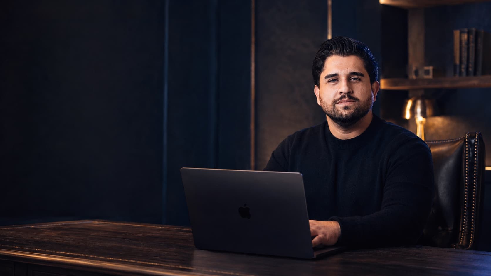 Gestor de tráfego da Tellus sentado à mesa do escritório, à noite, trabalhando no notebook